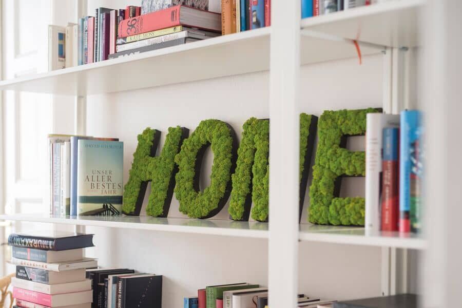 Schriftzum HOME aus Moos-Piktogrammen im Bücherregal